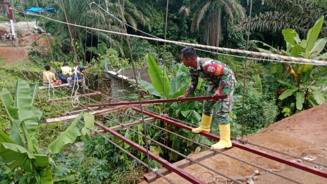 Bahu Membahu Demi Kemajuan Desa, Babinsa dan Warga Pasang Tali Seling Jembatan Gantung Bosar Galugur.